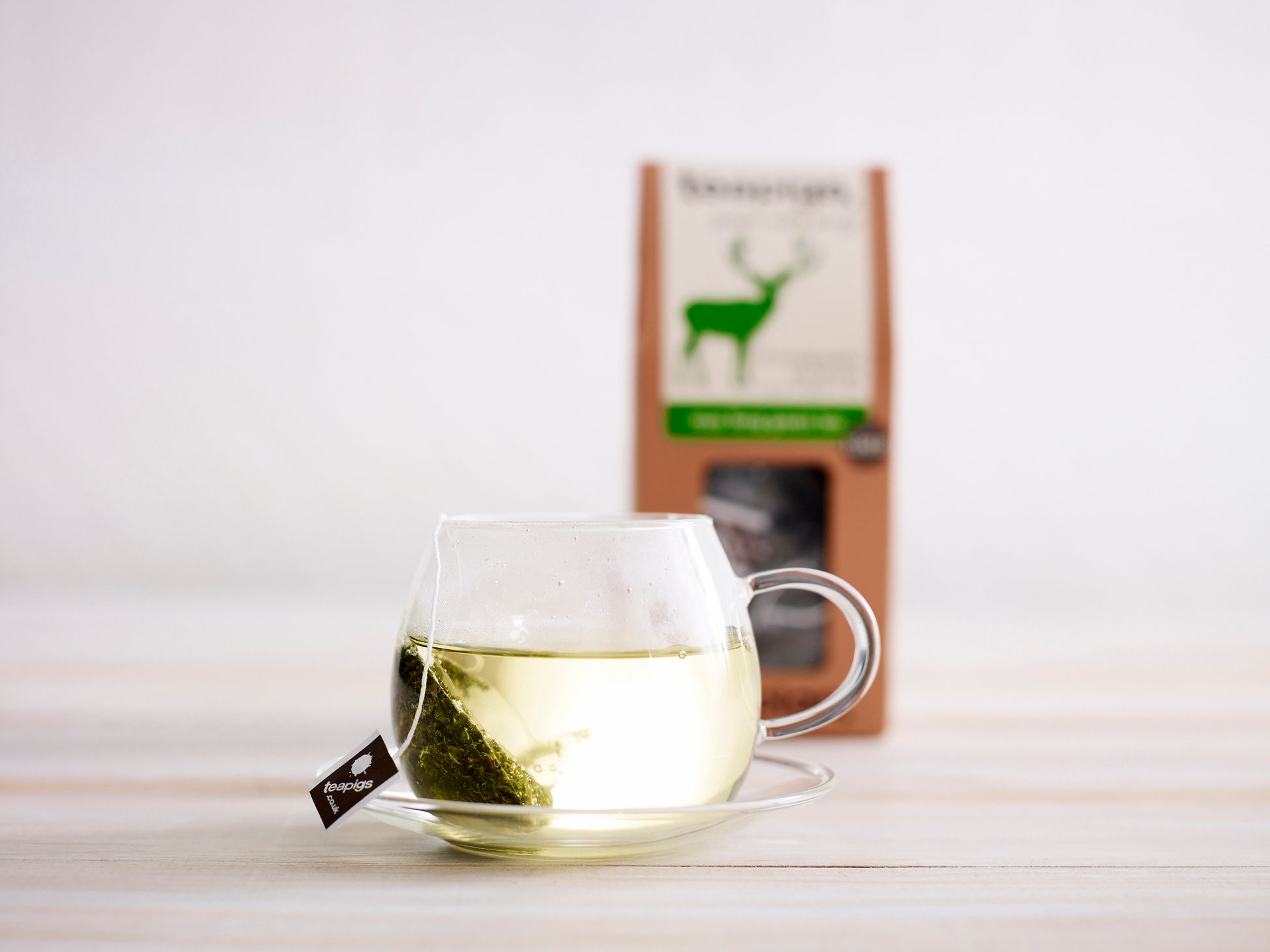 teapigs Mao Feng grøn te i glaskop med mao feng pakke i baggrunden